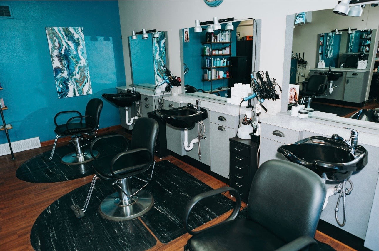 Salon interior with black chairs, mirrors, and hairdressing equipment.
